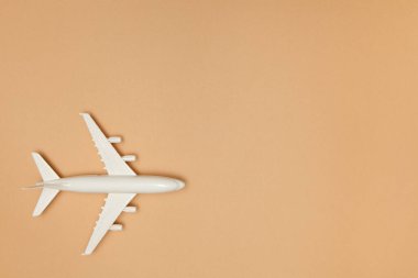 Uçak modeli. Kahverengi arka planda beyaz uçak. Seyahat tatili konsepti. Yaz dönemi. Düz konum, üst görünüm, kopyalama alanı.