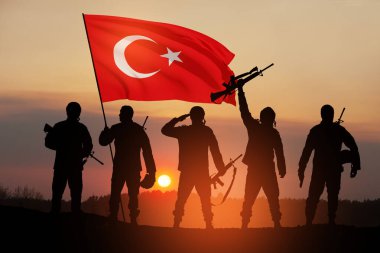 Silhouettes of soldiers with Turkey flag against the sunrise or sunset. Concept of crisis of war and conflicts between nations. Greeting card for Turkish Armed Forces Day, Victory Day.