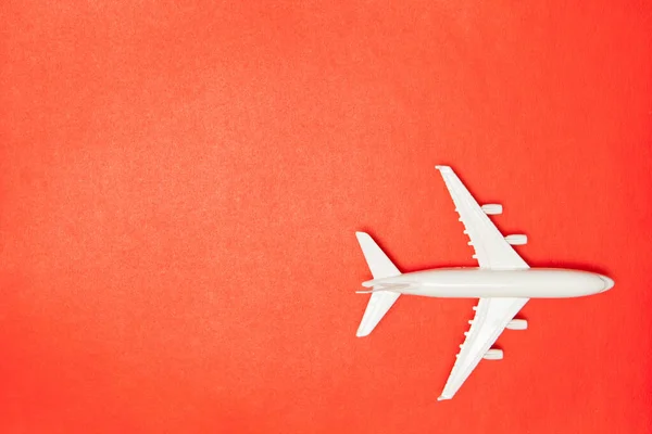 Airplane model. White plane on red background. Travel vacation concept. Summer background. Flat lay, top view, copy space.