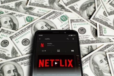 Netflix logo on smartphone screen. Netflix streaming service for watching videos. Smartphone on background of dollars. Moscow, Russia - April 21, 2022.