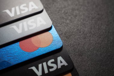 Visa kredi kartlarının ve kredi kartlarının yakın çekimleri koyu bir arkaplana yerleştirilmiş. Makro fotoğraf. Moskova, Rusya - 14 Mart 2022.