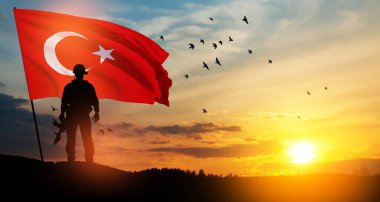 Gün batımında Türkiye bayrağı taşıyan asker silueti. Savaş krizi kavramı ve uluslar arasındaki siyasi çatışmalar. Türk Silahlı Kuvvetleri Günü için tebrik kartı, Zafer Günü.