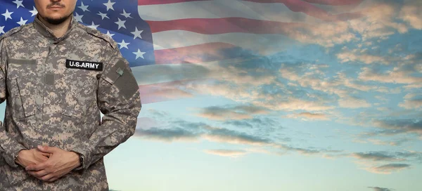 USA soldier in uniform on sunset sky background with USA flag. Memorial Day or Veterans day concept.