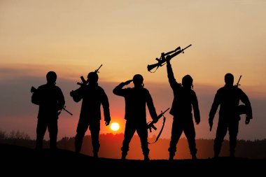 Silhouettes of soldiers standing against the backdrop of a sunset. Greeting card for Veterans Day, Memorial Day, Independence Day. USA celebration. Concept - patriotism, protection, remember honor.