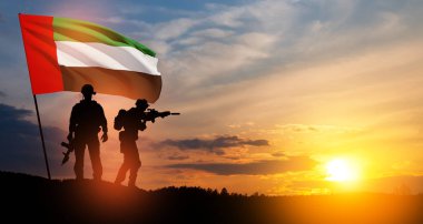 Silhouettes of soldiers with the flag of UAE against sunset or sunrise. Concept of national holidays. Commemoration Day.