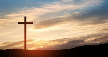 Christian cross on hill outdoors at sunrise. Resurrection of Jesus. Concept photo.