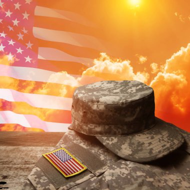 USA military uniform with insignias on old wooden table on sunset sky background with USA flag. Memorial Day or Veterans day concept.