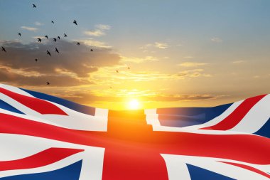 National flags of United Kingdom with flying birds on sunset sky background. Background with place for your text. 3d rendering.