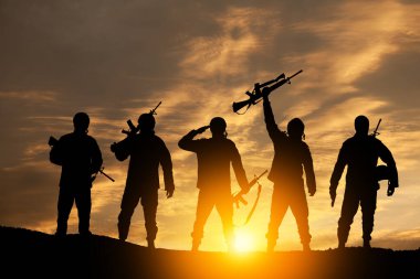 Silhouettes of soldiers standing against the backdrop of a sunset. Greeting card for Veterans Day, Memorial Day, Independence Day. USA celebration. Concept - patriotism, protection, remember honor.
