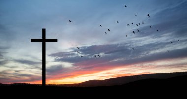 Christian cross on hill outdoors at sunrise. Resurrection of Jesus. Concept photo.