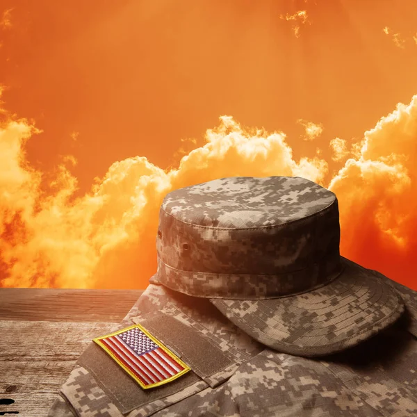 日没の空の背景にある古い木製のテーブルの上に記章とアメリカ軍の制服 記念日又は退役軍人の日の概念 — ストック写真