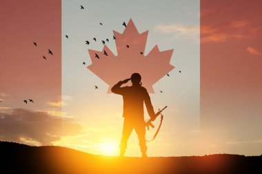 Canada army soldier saluting on a background of sunset or sunrise and Canada flag. Greeting card for Poppy Day, Remembrance Day. Canada celebration. Concept - patriotism, honor.