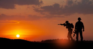 Silhouettes of soldiers standing against the backdrop of a sunset. Greeting card for Veterans Day, Memorial Day, Independence Day. USA celebration. Concept - patriotism, protection, remember honor.