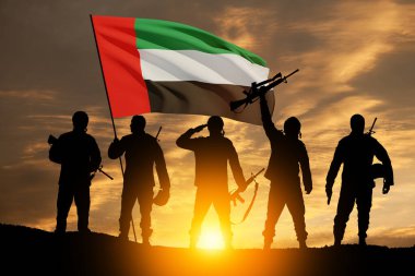 Silhouettes of soldiers with the flag of UAE against sunset or sunrise. Concept of national holidays. Commemoration Day.