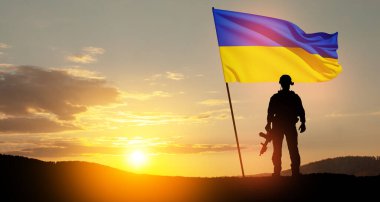 Flag of Ukraine with silhouette of soldier against the sunrise or sunset. Concept - armed forces of Ukraine. Relationship between Ukraine and Russia.