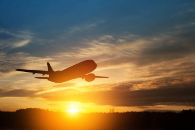 Uçak gün batımında havalanıyor. Gökyüzündeki uçağın silueti.