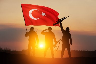 Silhouettes of soldiers with Turkey flag against the sunrise or sunset. Concept of crisis of war and conflicts between nations. Greeting card for Turkish Armed Forces Day, Victory Day.