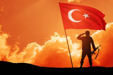Güneş doğarken ya da batarken Türkiye bayrağı taşıyan asker silueti. Savaş krizi kavramı ve uluslar arasındaki çatışmalar. Türk Silahlı Kuvvetleri Günü için tebrik kartı, Zafer Günü.