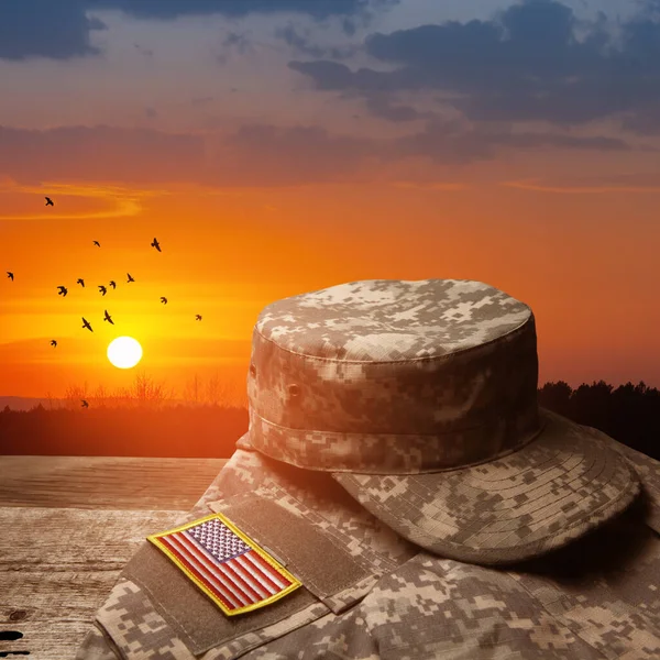 USA military uniform with insignias on old wooden table on sunset sky background with flying birds. Memorial Day or Veterans day concept.