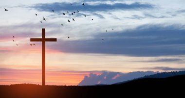 Christian cross on hill outdoors at sunrise. Resurrection of Jesus. Concept photo.