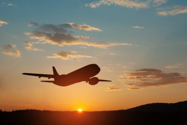 Uçak gün batımında havalanıyor. Gökyüzündeki uçağın silueti.