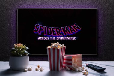 TV ekranında Örümcek Adam 'ın Örümcek Ayeti fragmanı ya da filmi oynanıyor. Uzaktan kumandalı televizyon, patlamış mısır kutuları ve ev bitkisi. Astana, Kazakistan - 15 Mayıs 2023.