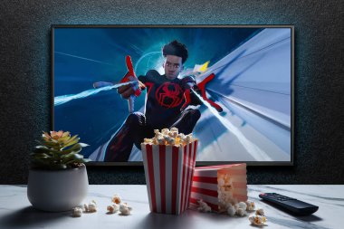 TV ekranında Örümcek Adam 'ın Örümcek Ayeti fragmanı ya da filmi oynanıyor. Uzaktan kumandalı televizyon, patlamış mısır kutuları ve ev bitkisi. Astana, Kazakistan - 15 Mayıs 2023.