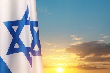 Israel flag with a star of David over cloudy sky background on sunset. Patriotic concept about Israel with national state symbols. Banner with place for text.