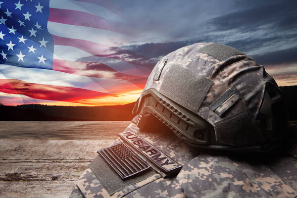 Военная форма США со знаками отличия на старом деревянном столе на фоне заката неба с флагом США. День памяти или День ветеранов.