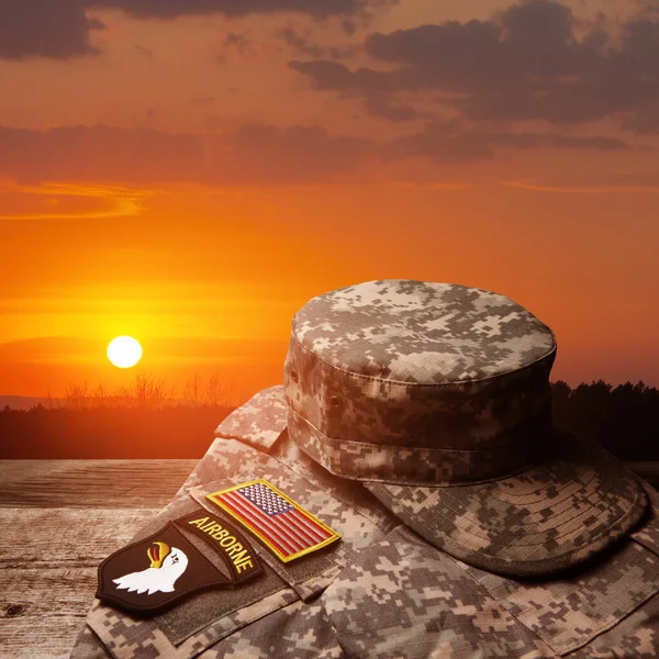 日没の空の背景にある古い木製のテーブルの上に記章とアメリカ軍の制服 記念日又は退役軍人の日の概念 — ストック写真