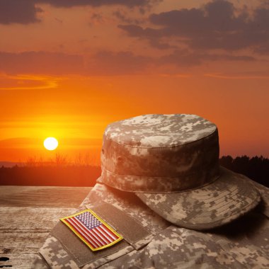 USA military uniform with insignias on old wooden table on sunset sky background. Memorial Day or Veterans day concept.