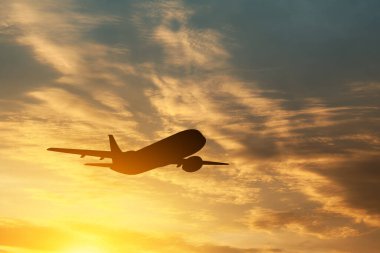 Uçak gün batımında havalanıyor. Gökyüzündeki uçağın silueti.