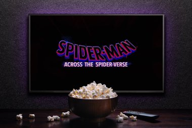 TV ekranında Örümcek Adam 'ın Örümcek Ayeti fragmanı ya da filmi oynanıyor. Uzaktan kumandalı televizyon ve patlamış mısır kasesi. Astana, Kazakistan - 15 Mayıs 2023.