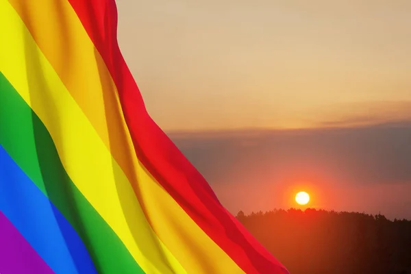 日没の空にLgbtの誇りフラグを振って 虹のフラグの背景 多色の平和旗運動 オリジナルカラーシンボル — ストック写真