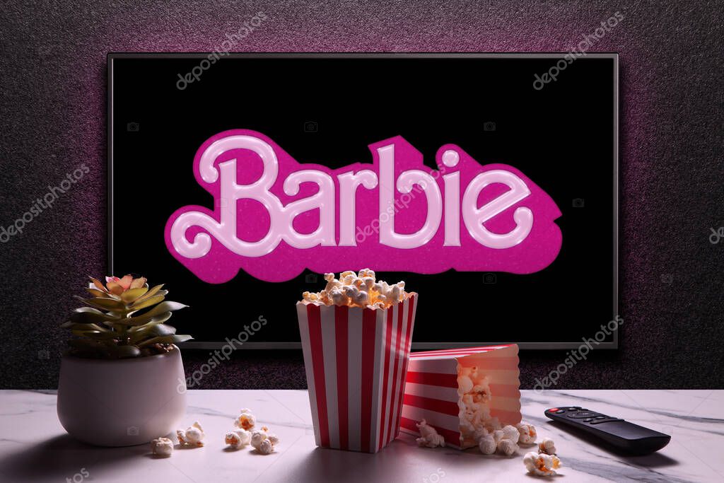 TV screen playing Barbie trailer or movie. TV with remote control, popcorn boxes and home plant. Astana, Kazakhstan - July 2, 2023.
