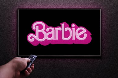 Televizyon ekranında Barbie karavanı ya da film oynanıyor. Adam uzaktan kumandayla televizyonu açıyor. Astana, Kazakistan - 2 Temmuz 2023.