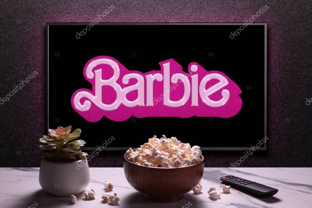 TV screen playing Barbie trailer or movie. TV with remote control, popcorn bowl and home plant. Astana, Kazakhstan - July 2, 2023.