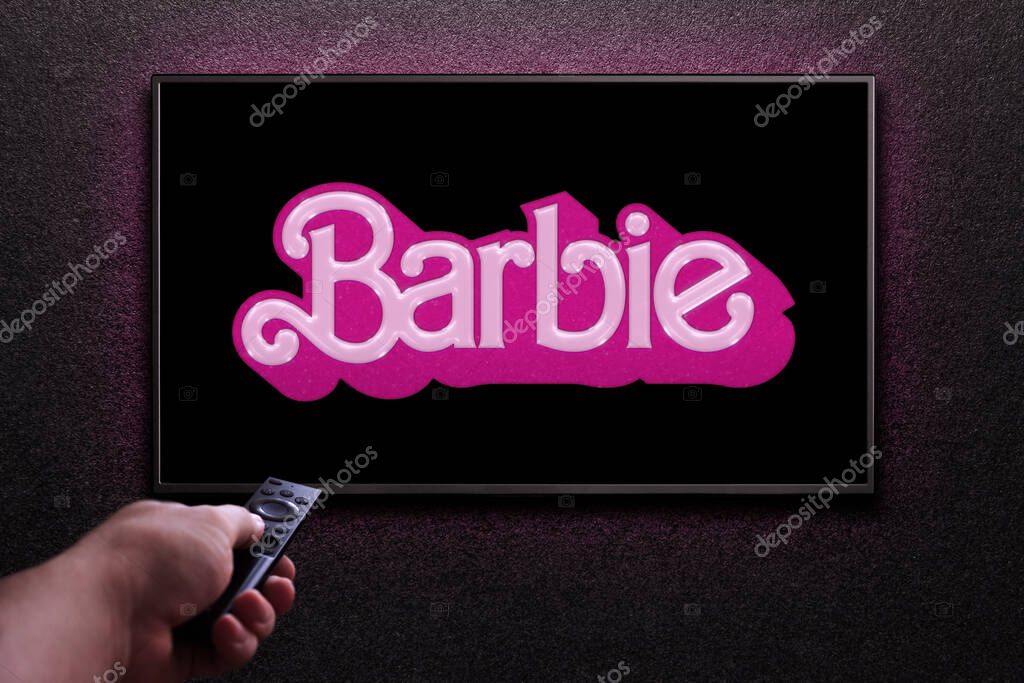 TV screen playing Barbie trailer or movie. Man turns on TV with remote control. Astana, Kazakhstan - July 2, 2023.