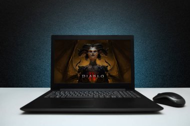 Diablo 4 oyunu ekrandaki dizüstü bilgisayarda, siyah desenli duvarda mavi ışık olan fareyle oynanacak. Diablo 4, Sony 'nin en ünlü RPG oyun serilerinden biri. Astana, Kazakistan - 2 Temmuz 2023.