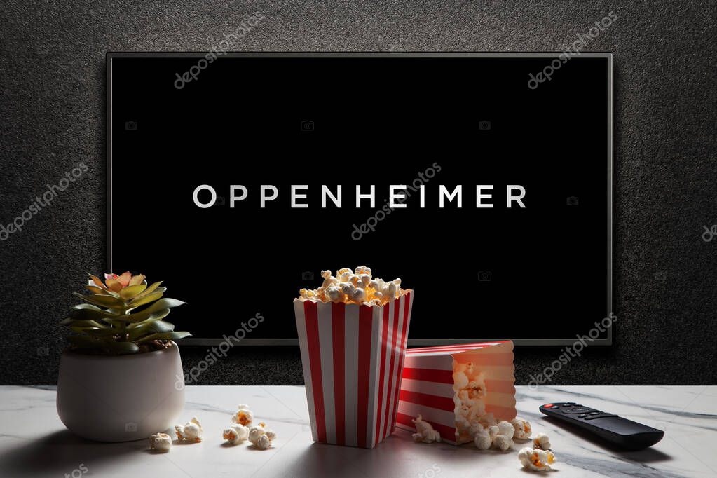 Oppenheimer trailer or movie. TV with remote control, popcorn boxes and home plant. Astana, Kazakhstan - July 2, 2023.