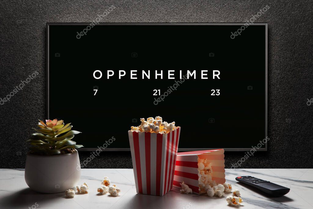 Oppenheimer trailer or movie. TV with remote control, popcorn boxes and home plant. Astana, Kazakhstan - July 2, 2023.