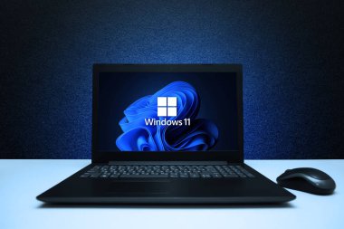 Ekran dizüstü bilgisayarındaki 11 numaralı logoda mavi ışıkla kaplı siyah desenli duvarda fare resmi var. Microsoft 'tan yeni bir işletim sistemi güncellemesi. Astana, Kazakistan - 2 Temmuz 2023.