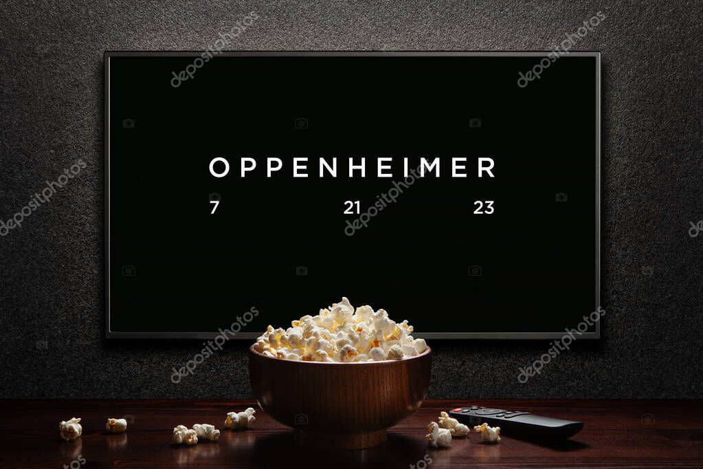 Oppenheimer trailer or movie. TV with remote control and popcorn bowl. Astana, Kazakhstan - July 2, 2023.