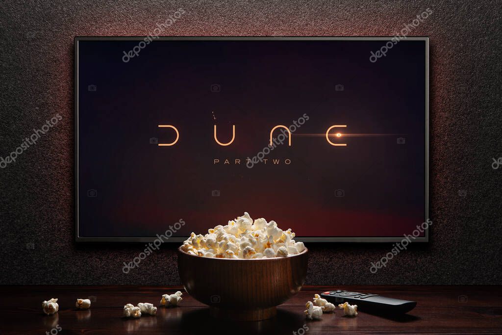 TV screen playing Dune Part Two trailer or movie. TV with remote control and popcorn bowl. Astana, Kazakhstan - May 15, 2023.