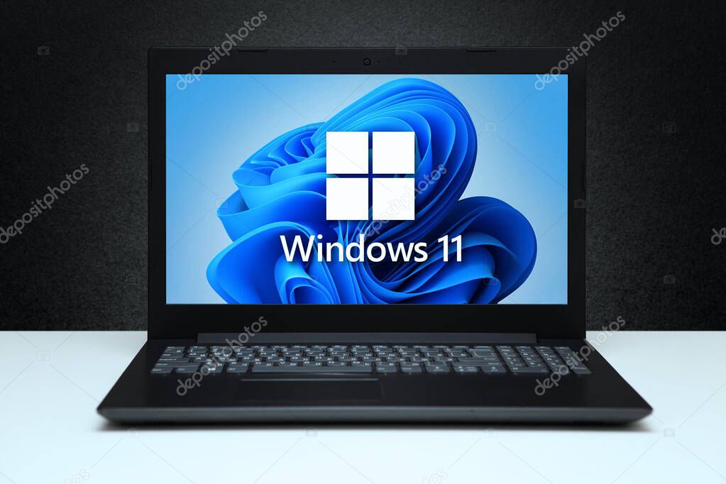 Windows 11 logo on the screen laptop computer black textured wall with white light. A new operating system update from Microsoft. Astana, Kazakhstan - July 2, 2023.
