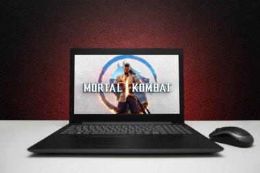 Mortal Kombat 1 oyunu ekrandaki dizüstü bilgisayarda, siyah desenli duvardaki fareli kırmızı ışıkla oynanacak. Astana, Kazakistan - 2 Temmuz 2023.