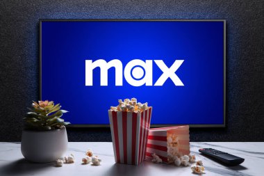 Max ya da HBO Max logosu TV 'de patlamış mısır kutuları, uzaktan kumanda ve masada ev bitkisi var. HBO Max, Amerika Birleşik Devletleri 'ne bağlı bir abonelik videosu. Astana, Kazakistan - 21 Temmuz 2023.