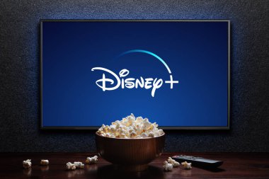 Disney artı TV 'de patlamış mısır kasesi ve masada uzaktan kumanda ile logo. Disney Plus bir Amerikan abonelik videosu yayınlama servisidir. Astana, Kazakistan - 21 Temmuz 2023.