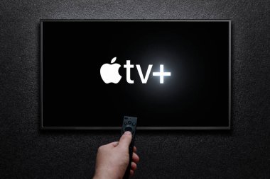 Apple TV artı TV ekranında logo. Adam uzaktan kumandayla televizyonu açıyor. Apple TV + bir Amerikan abonelik yayın hizmetidir. Astana, Kazakistan - 21 Temmuz 2023.
