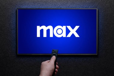 Max veya HBO Max logosu TV ekranında. Adam uzaktan kumandayla televizyonu açıyor. HBO Max, Amerika Birleşik Devletleri 'ne bağlı bir abonelik videosu. Astana, Kazakistan - 21 Temmuz 2023.